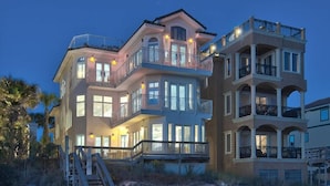 A multi-story beachfront property with balconies, large windows, and a staircase leading to the entrance. - Millenia 7 Bedroom Holiday Home by Five Star Properties (Destin)