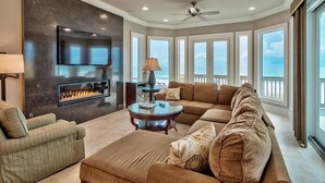 A spacious living room with a fireplace, a large sofa, a coffee table, and a television mounted on the wall. - Millenia 7 Bedroom Holiday Home by Five Star Properties (Destin)