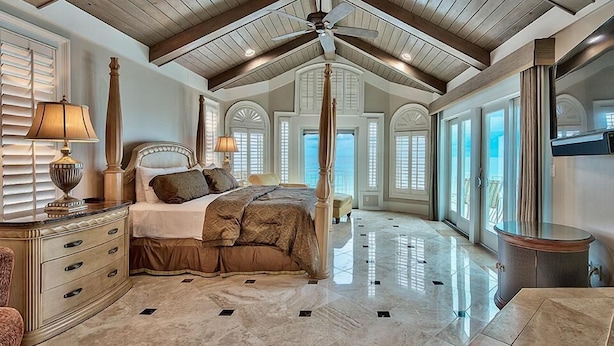 A spacious bedroom with a large bed, a ceiling fan, and a view of the outdoors through large windows. - Millenia 7 Bedroom Holiday Home by Five Star Properties (Destin)