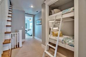 A bedroom with bunk beds, a wooden staircase, and a hallway leading to another room. - MIRAMAR BEACH VILLAS 103 4 Bedroom Holiday Home by Five Star Properties (Miramar Beach)