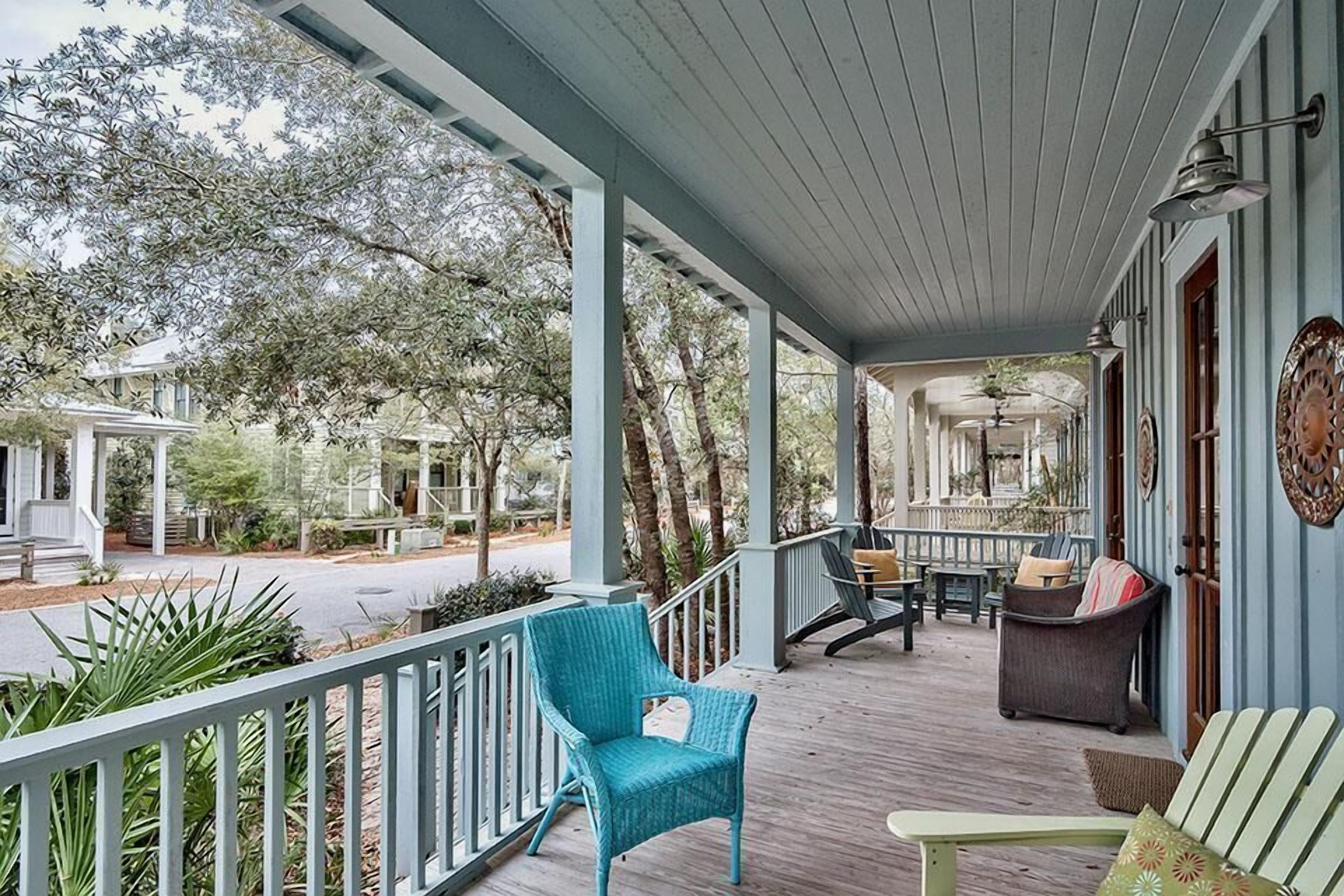 A covered porch with a railing, outdoor seating, and a view of the surrounding area.