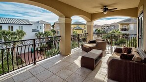A balcony with wicker furniture, a ceiling fan, and a view of neighboring houses. - Ocean Escape 4 Bedroom Holiday Home by Five Star Properties (Destin)