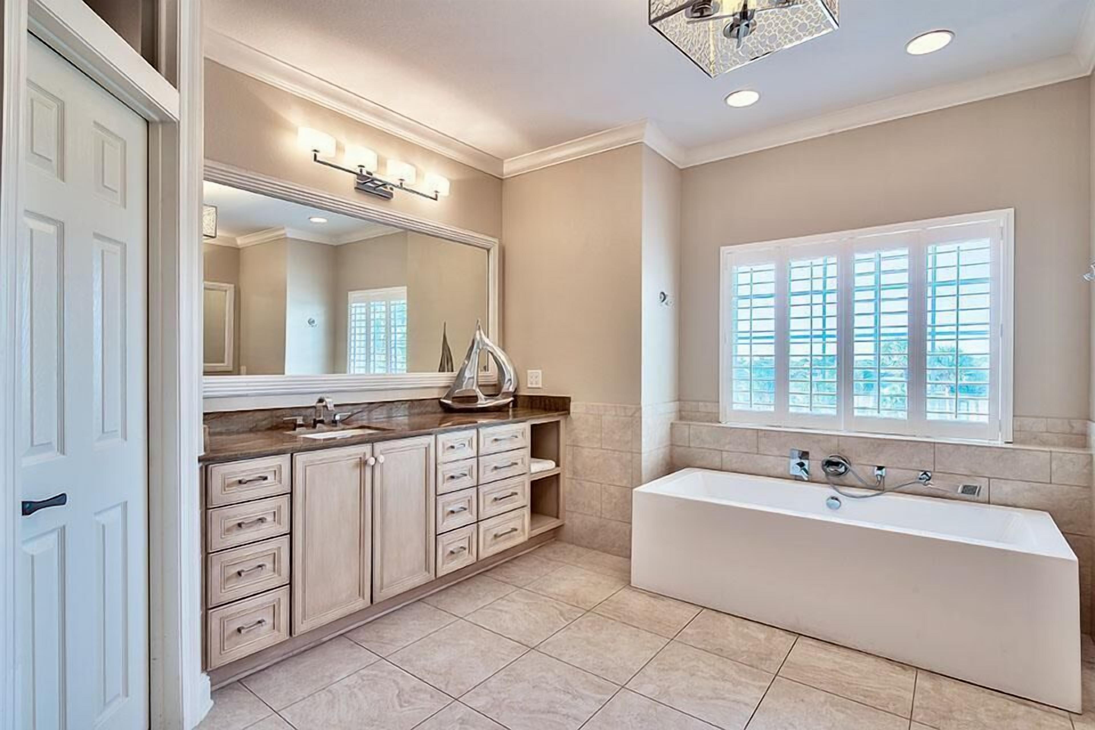 A spacious bathroom with a large bathtub, a double vanity with a mirror, and a window providing natural light.