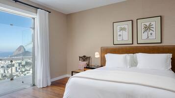 A hotel room with a large bed, a nightstand, a lamp, and two framed pictures of palm trees.