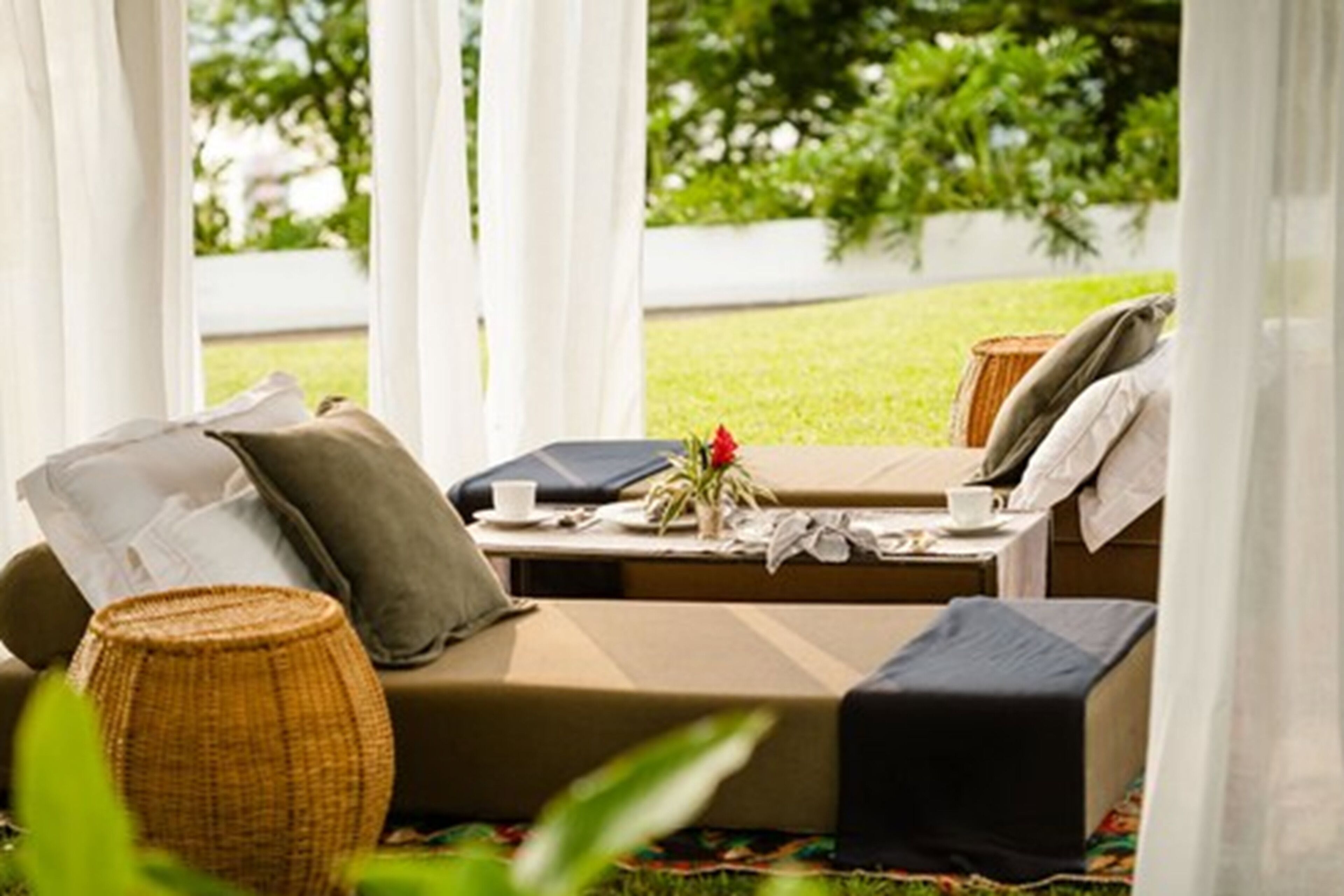 Un espace extérieur accueillant, aménagé avec un canapé et une table, et entouré de verdure.