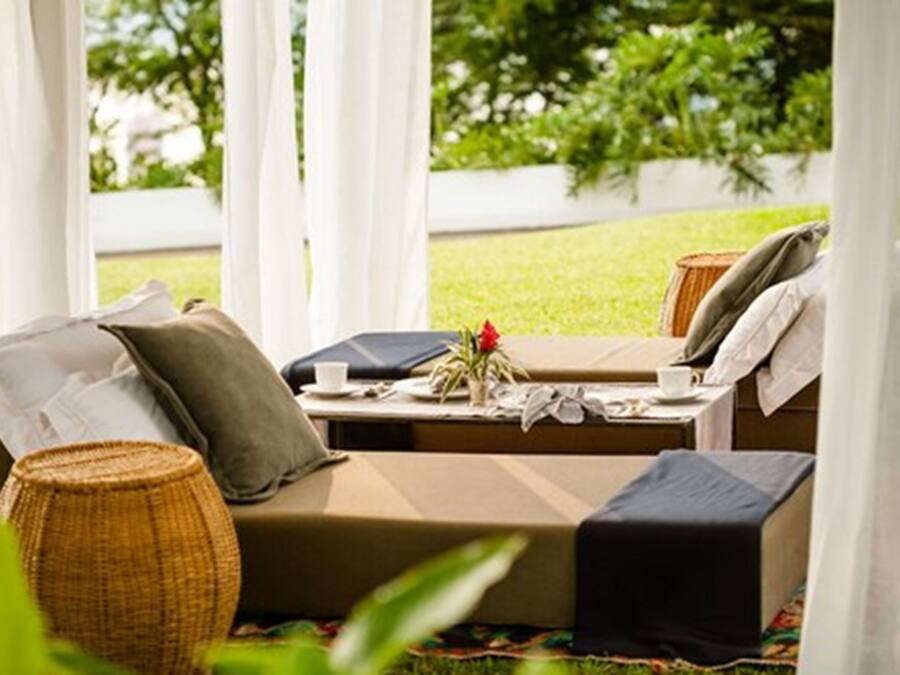Un espace extérieur accueillant, aménagé avec un canapé et une table, et entouré de verdure.