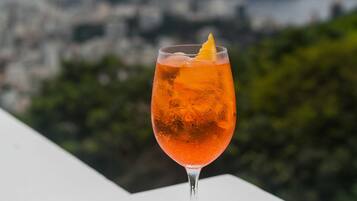 Un vaso de jugo de naranja con una rodaja de limón sobre una bandeja con dos cuencos de nueces.
