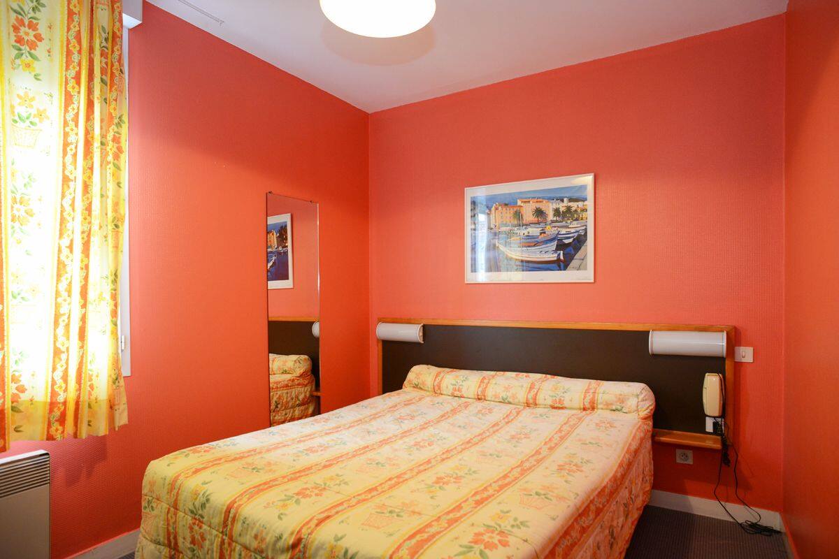 Ein Zimmer mit einem Bett, einem Gemälde, einem Spiegel und einem Telefon.