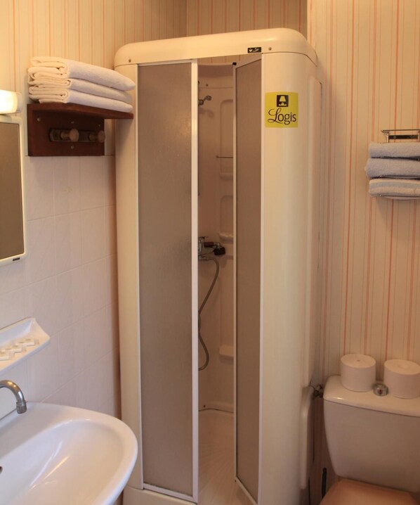 Un baño pequeño y cerrado con inodoro, lavamanos y cabina de ducha.