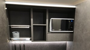 A compact kitchen with a microwave, stainless steel sink, and a small countertop. - Hotel Rinaldo Apartments (Borgomanero)