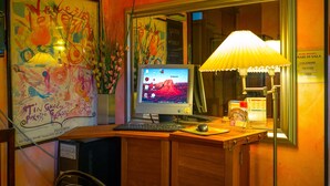 A hotel reception desk with a computer, a lamp, and a framed artwork. - Hotel Rinaldo Apartments (Borgomanero)