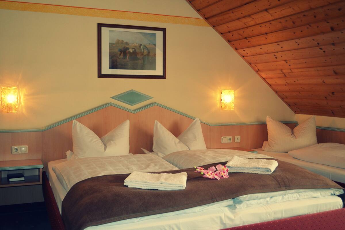 A hotel room with two beds, a wooden ceiling, and a painting on the wall.