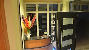 A hotel reception desk with a vase of flowers, a glass display case, and a sign that reads "HOTEL". - Rothsee Hotel (Allersberg)