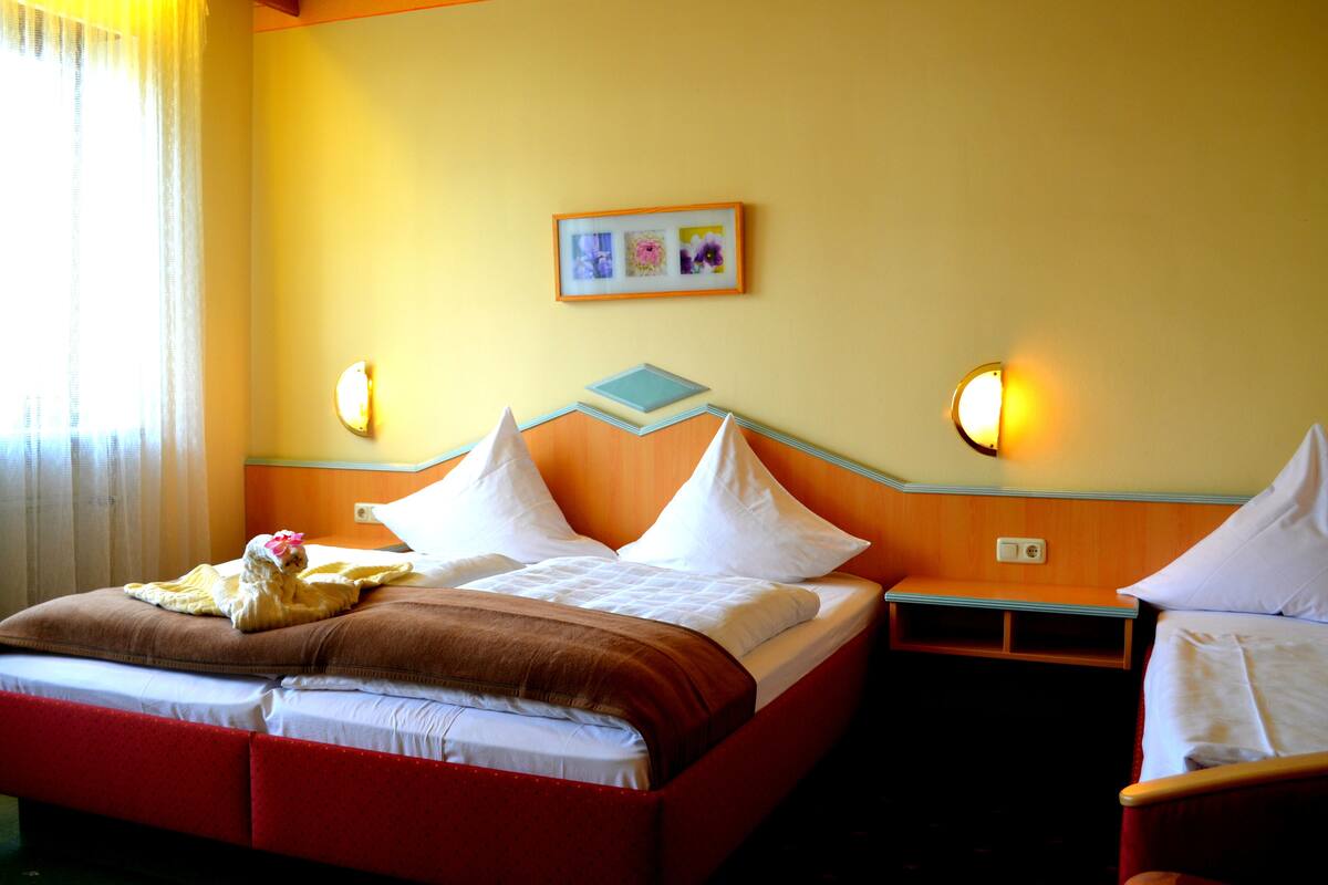 A hotel room with a bed, a nightstand, a chair, and a wall-mounted picture.