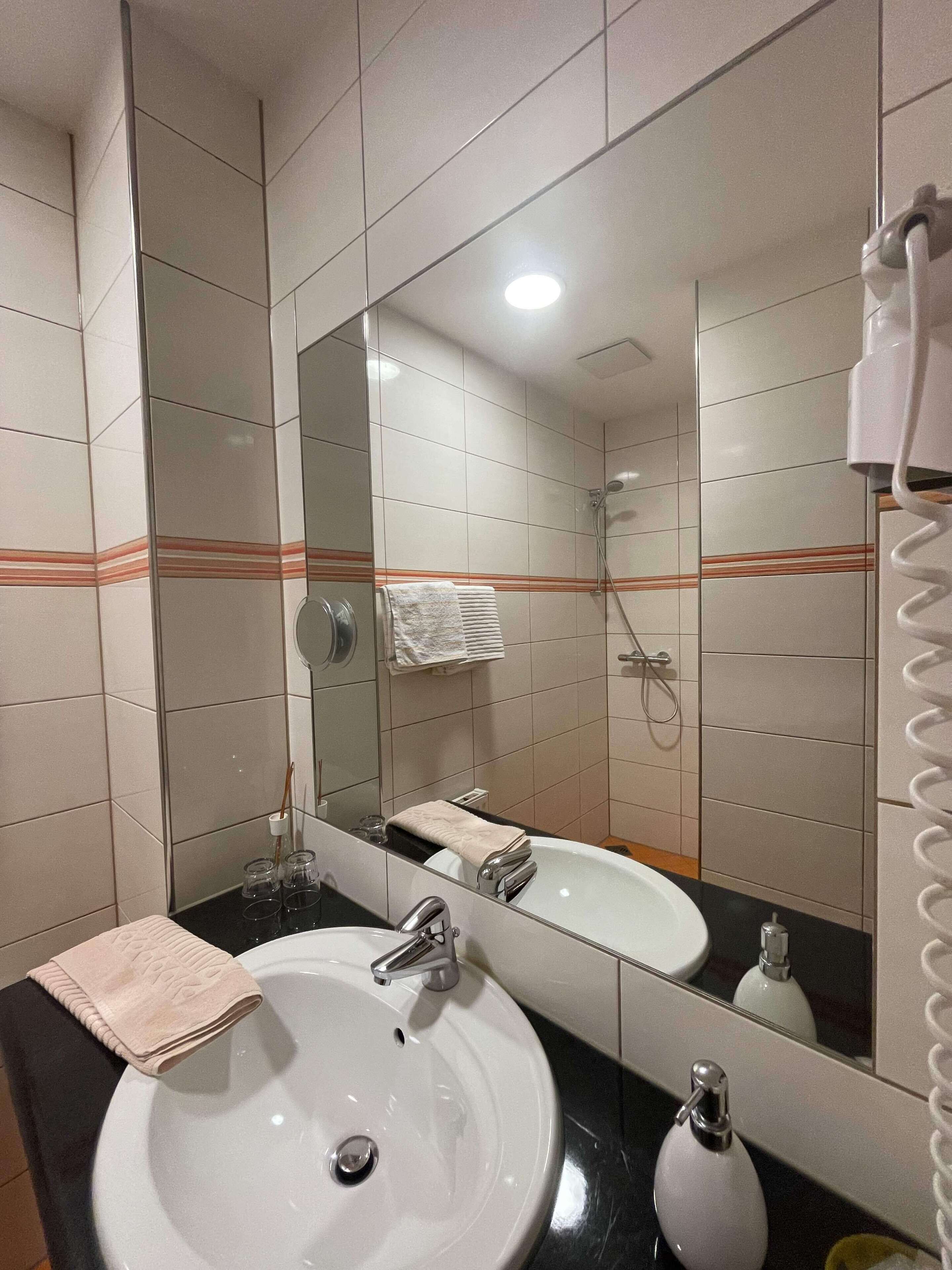 A bathroom with two sinks, a mirror, and a shower.