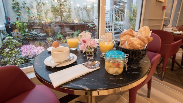 Una mesa de desayuno con cruasanes, un tarro de fruta, un bol y zumo de naranja.