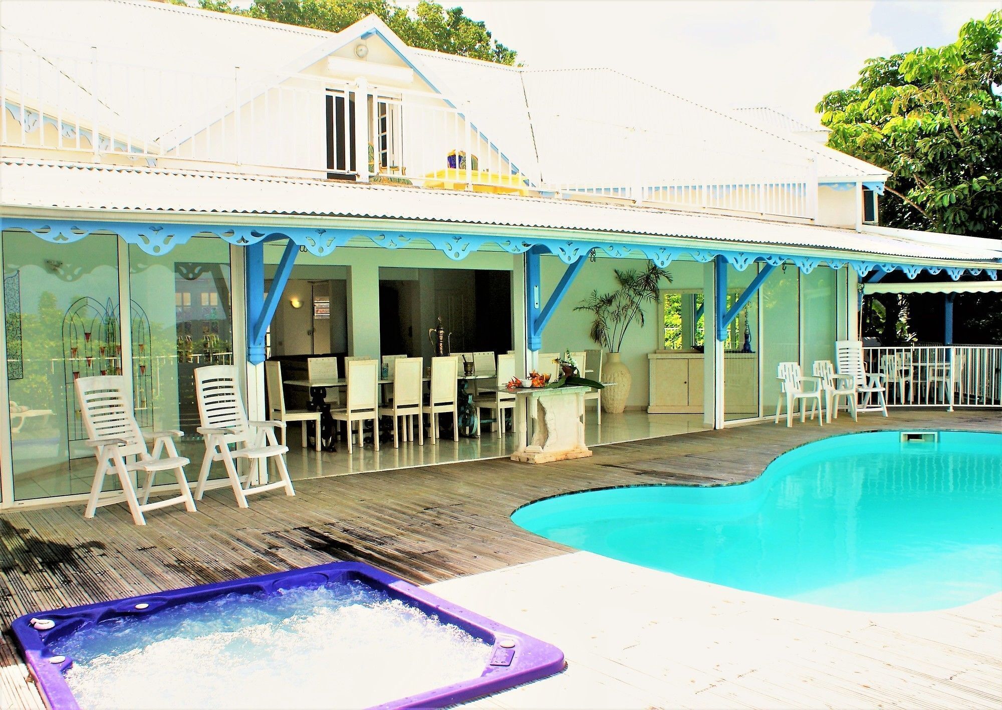 A pool area with lounge chairs, a hot tub, and a covered patio.