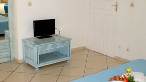 Una habitación con una cama, una mesita de noche y un televisor, y una puerta.