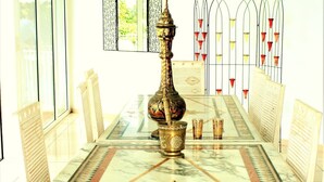 Un comedor con una mesa de mármol, sillas, un centro de mesa decorativo y una pared con diseño.