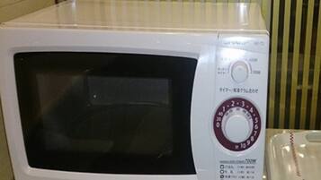 Un horno microondas blanco con un panel de control que incluye un temporizador y ajustes de potencia.