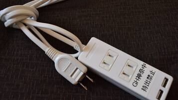 Een witte stekkerdoos met meerdere stopcontacten en een USB-aansluiting, geplaatst op een donkere stoffen ondergrond.