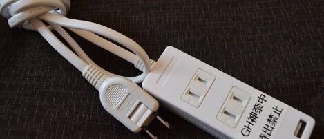 Una regleta blanca con múltiples enchufes y un puerto USB, sobre una superficie de tela oscura.