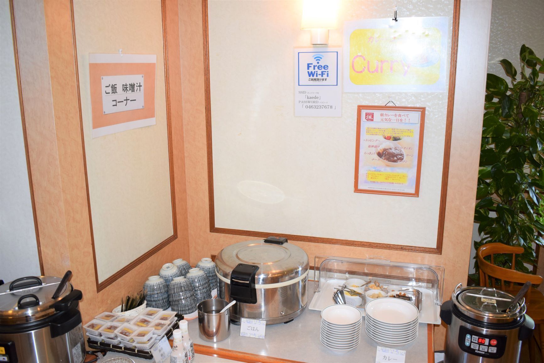 A buffet setup with various food containers, a rice cooker, and a sign offering free Wi-Fi.