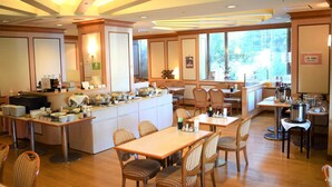 Zona de dinar d'hotel amb barra de buffet, diverses taules i cadires.