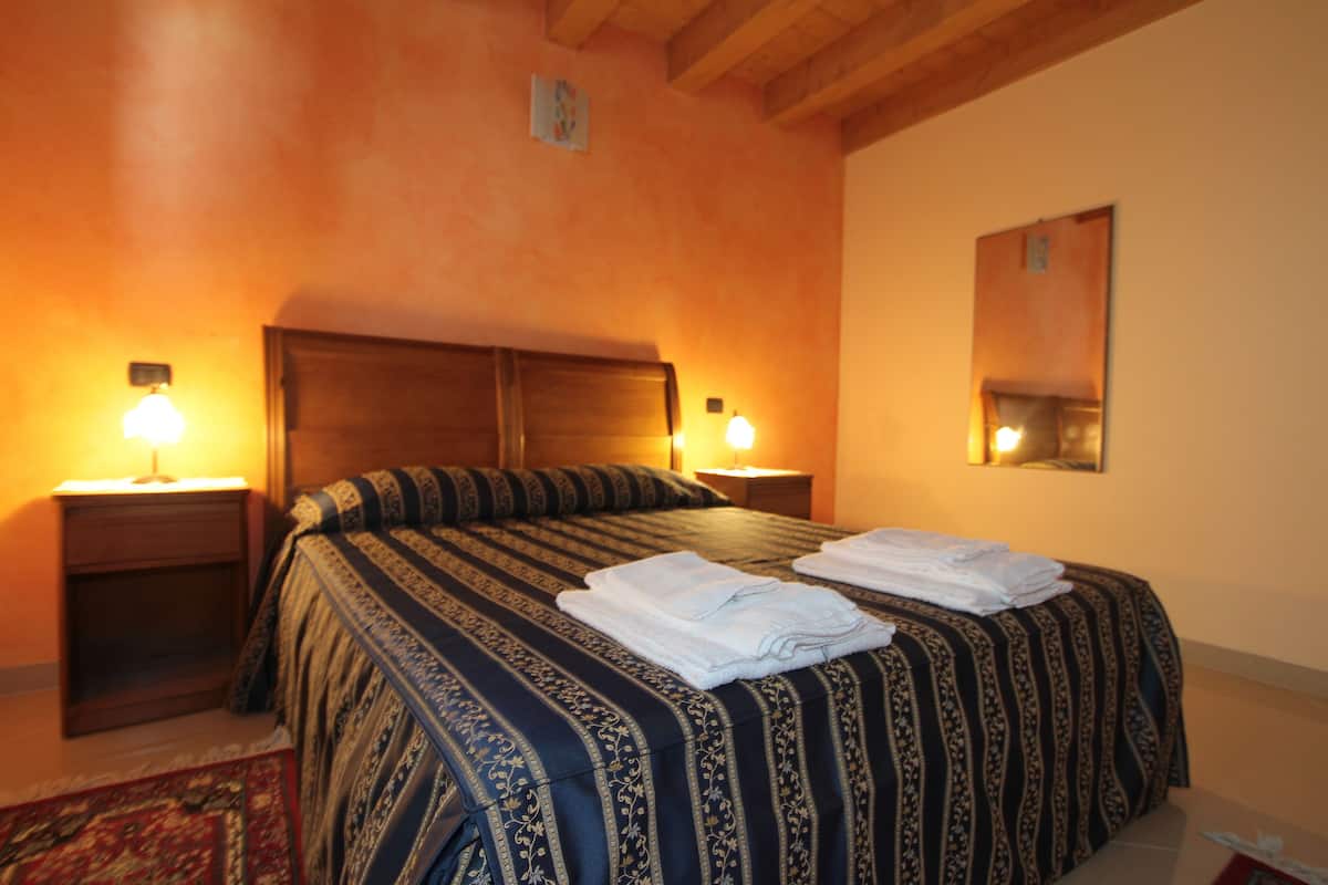 A hotel room with a large bed, two bedside tables, and a nightstand.