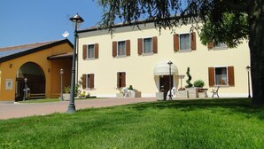 A building with a yellow facade, multiple windows with shutters, and a central entrance with a canopy. - Agriturismo Tre Rondini (Legnago)