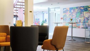 A modern lobby with contemporary chairs, a glass table, and a colorful abstract mural on the wall. - Akademiehotel Jena (Jena)