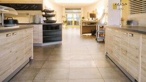 A modern kitchen with wooden cabinets, a central island, and a chalkboard menu. - Akademiehotel Jena (Jena)