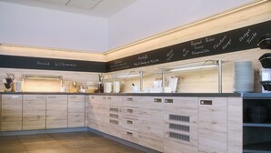 A modern, well-lit cafe with wooden cabinetry and a chalkboard menu. - Akademiehotel Jena (Jena)