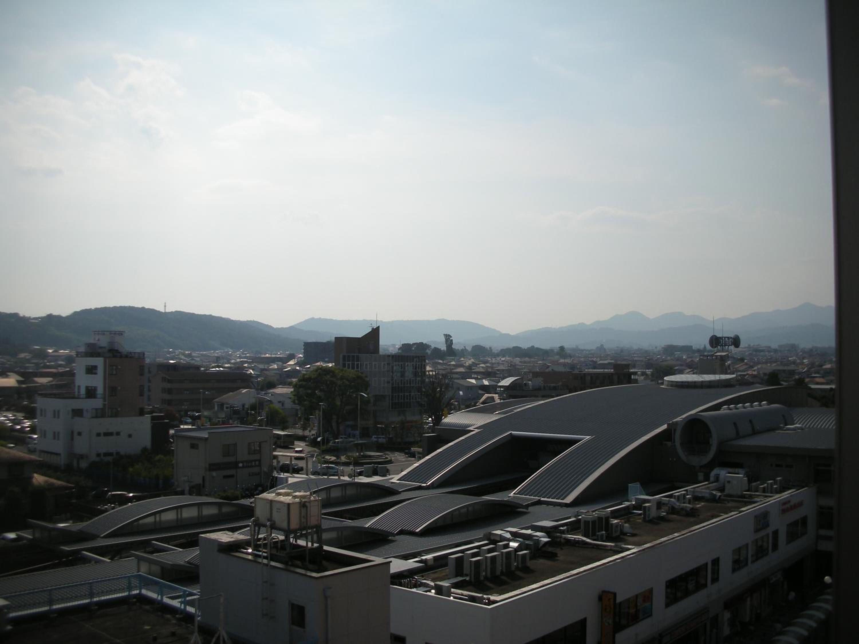 A cityscape with modern buildings, a prominent curved structure, and distant mountains.