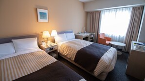 A hotel room with two beds, a desk, a chair, a small table, and a minibar. - Grand Hotel Kanachu Hadano (Hadano)