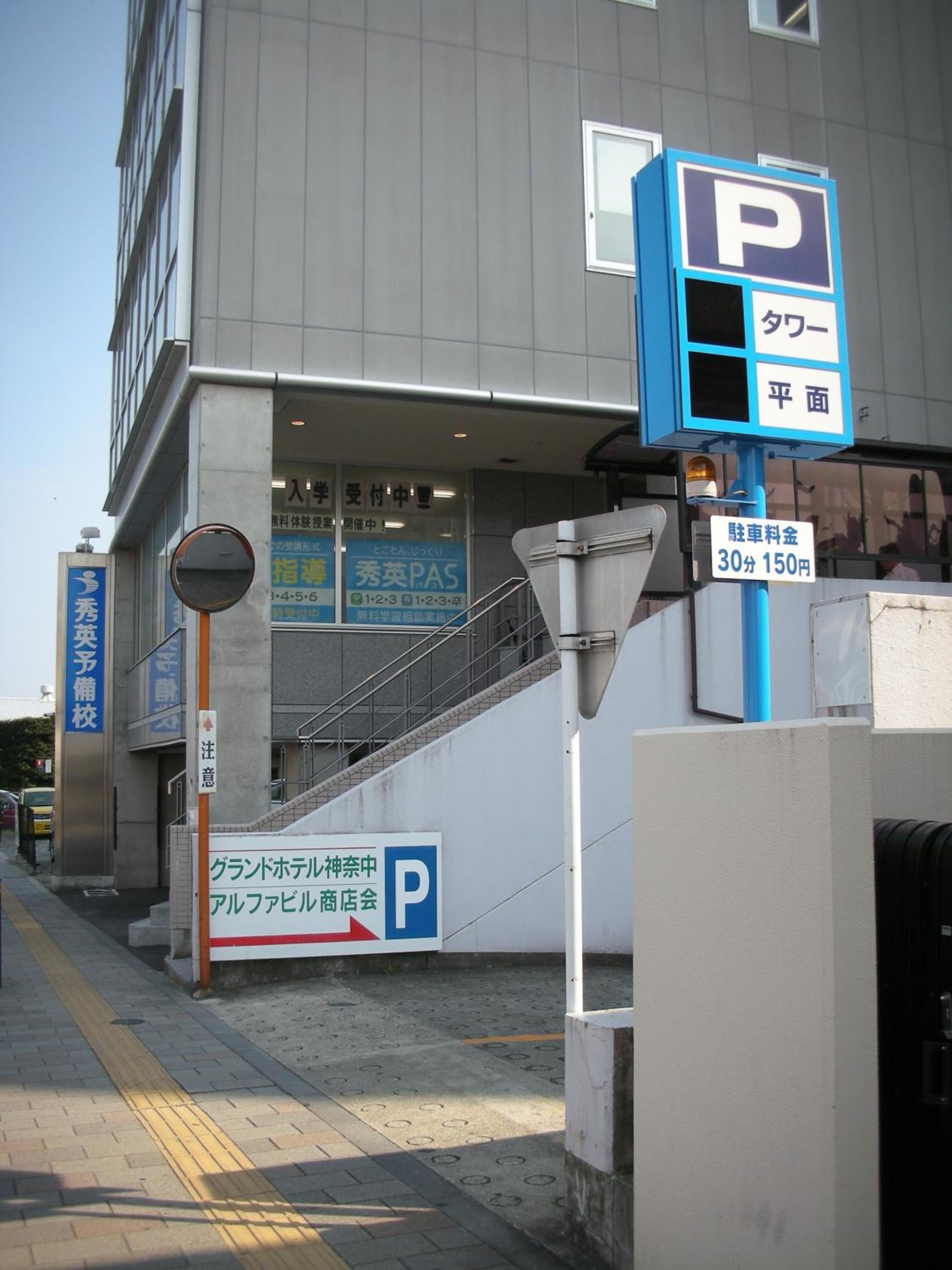 En bygning med parkeringsskilt, trappe og skilt der angiver en parkeringsafgift på 150 yen for 30 minutter.