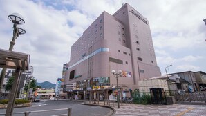 A multi-story hotel with a prominent entrance, a parking area, and a pedestrian walkway. - Grand Hotel Kanachu Hadano (Hadano)