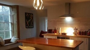 Una cocina moderna con una isla grande, dos taburetes de bar y una zona de comedor con ventanal.