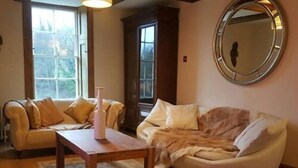 Una sala de estar acogedora con un sofá, un espejo redondo y una mesa de centro de madera.