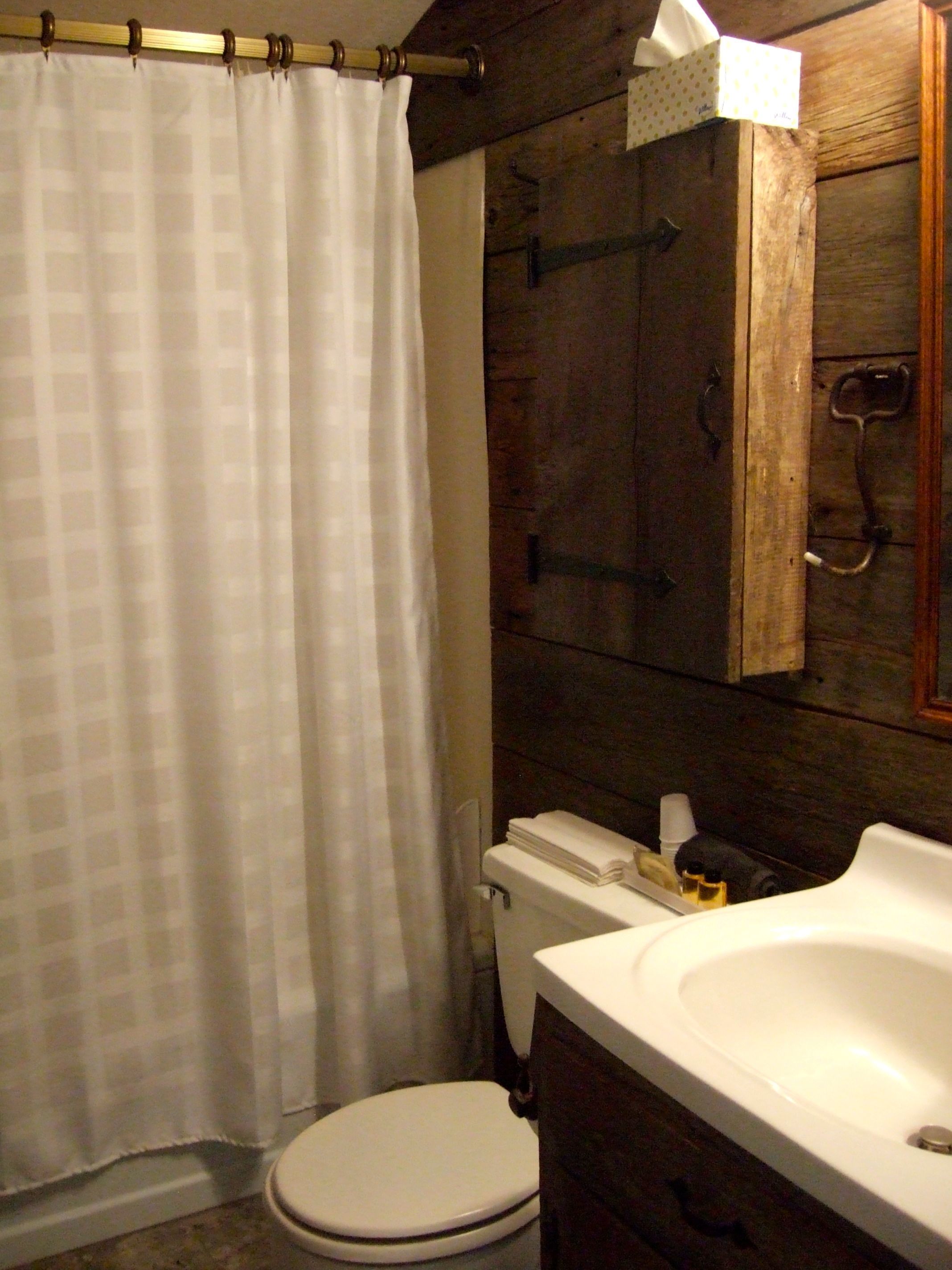 A bathroom with a white toilet, a wooden cabinet, and a white sink.