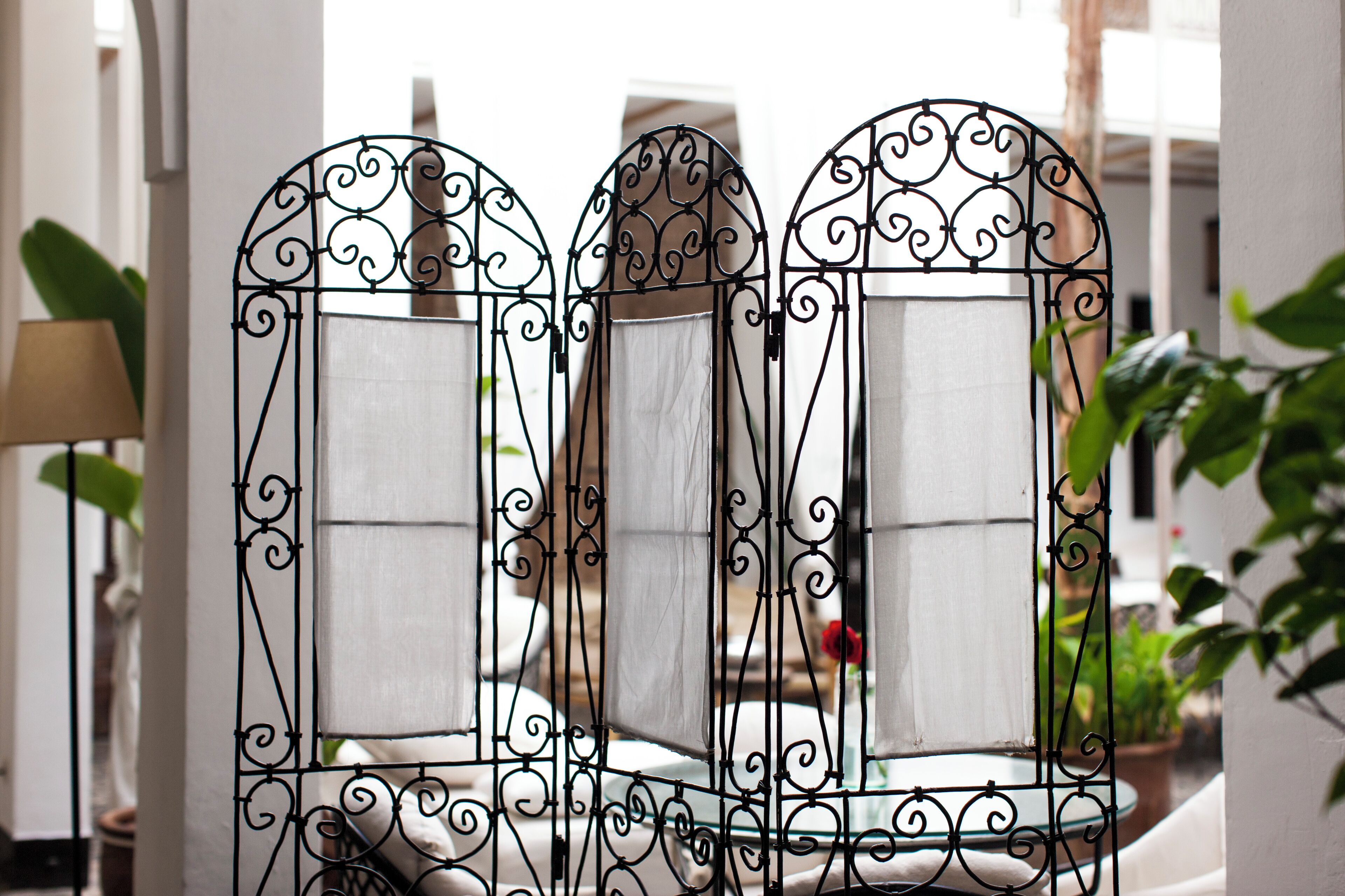 A room with a decorative metal partition featuring a mirror and a cushioned seat.