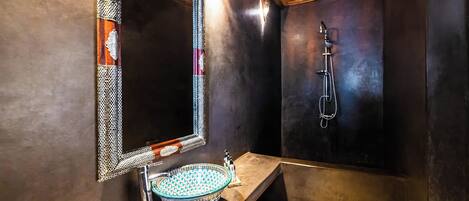 A modern bathroom with a large mirror, a vessel sink, and a shower.