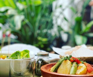 A table with a dish of vegetables, a glass, and a jar of spices.