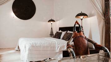Un dormitorio con una cama, dos lámparas de pared, una cabeza de toro decorativa y un espejo redondo.