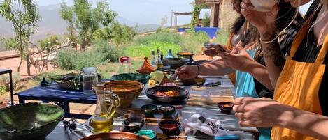 Una mesa de comedor con diversos platos y cubiertos, rodeada de gente.