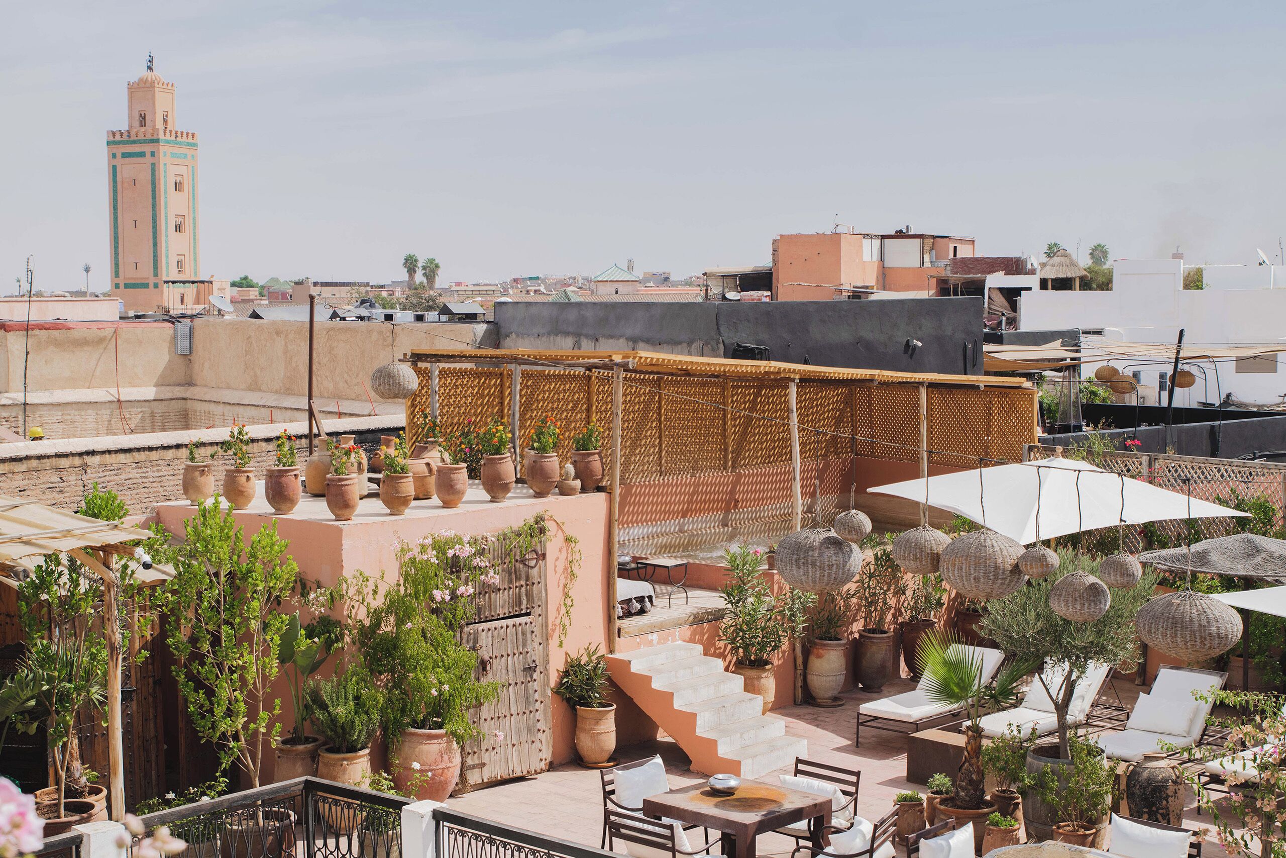 Terraza en la azotea con plantas en macetas, asientos exteriores y una vista de una torre a lo lejos.