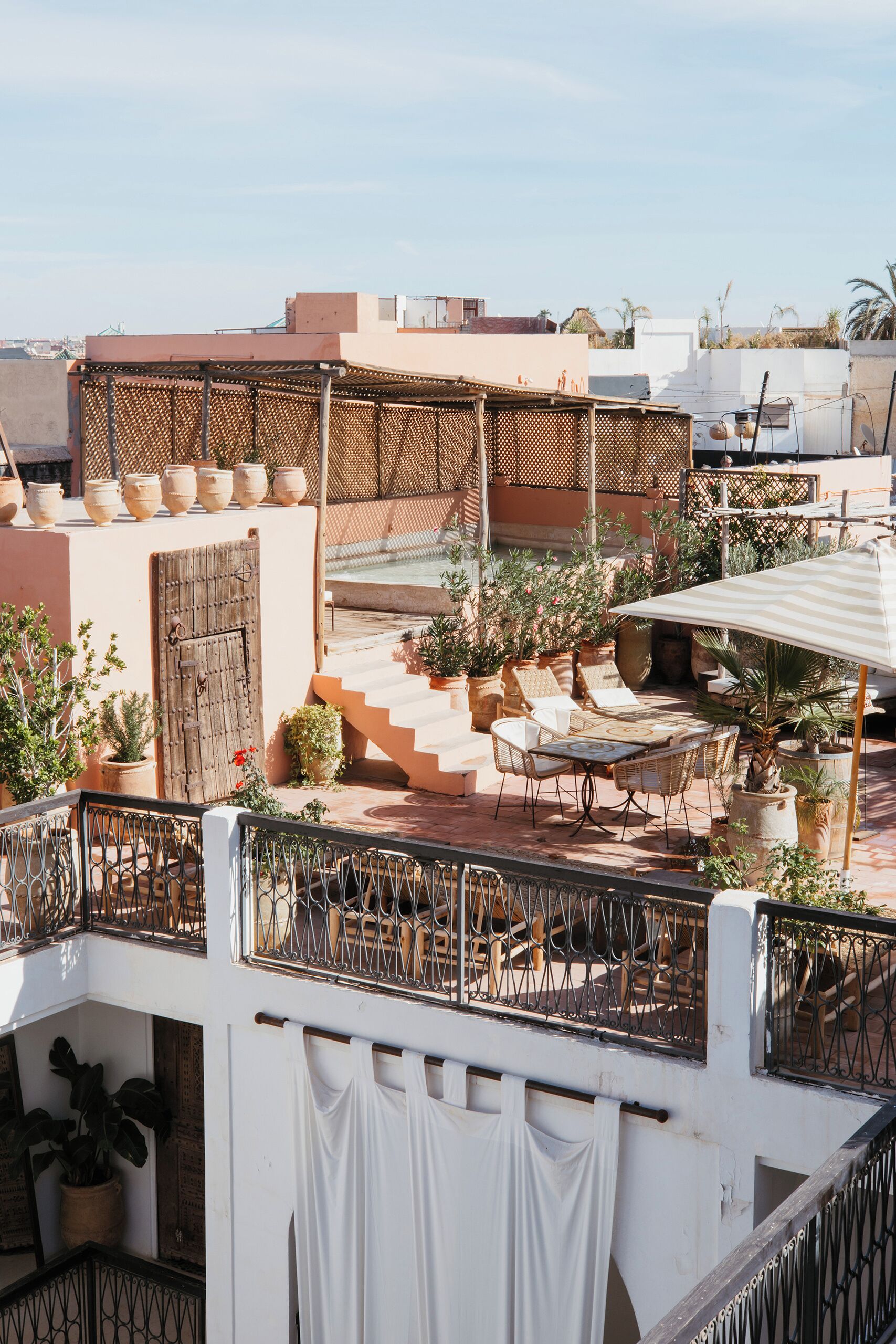 A rooftop terrace with outdoor seating, potted plants, and a view of the cityscape.
