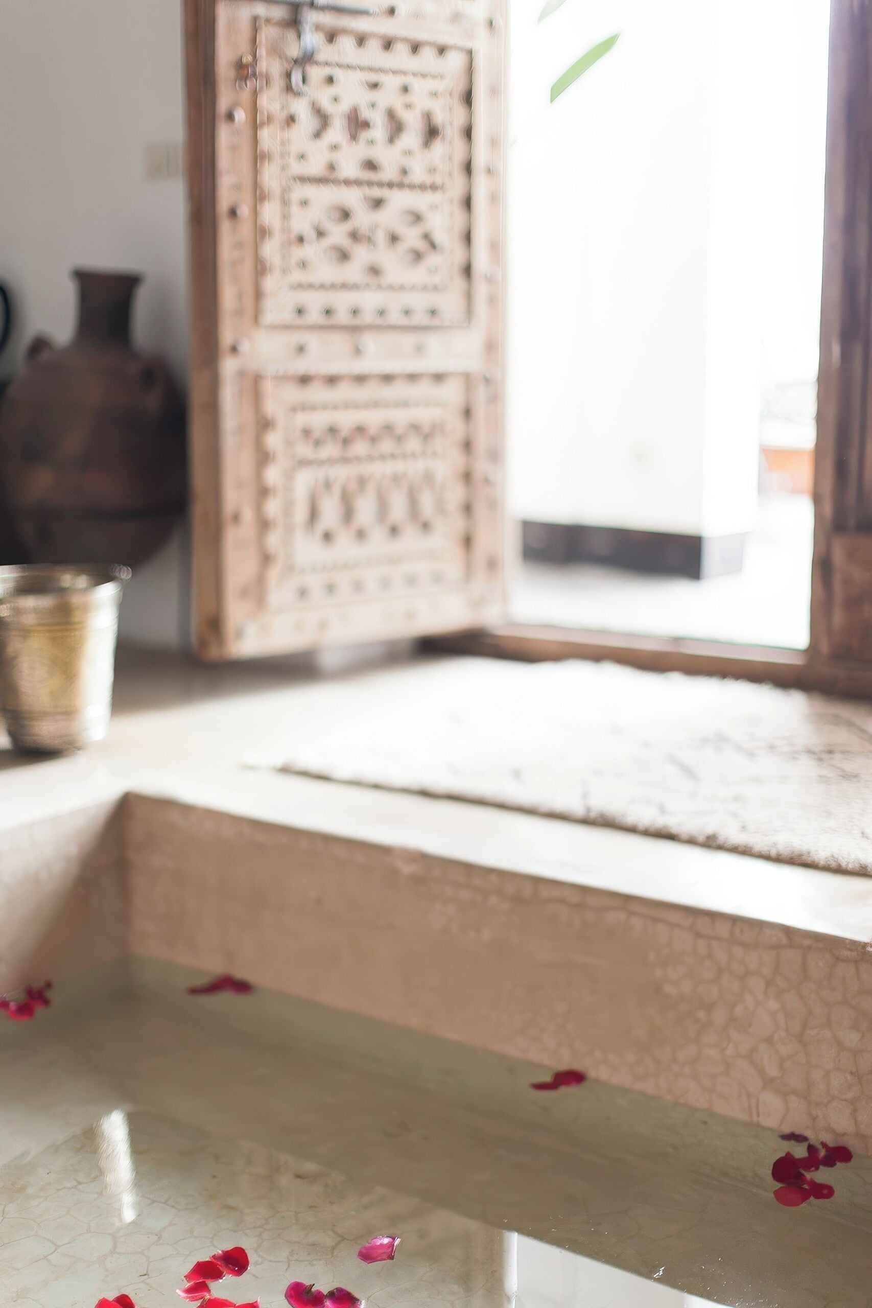 A room with a tiled floor, a wooden bench, and a decorative door.
