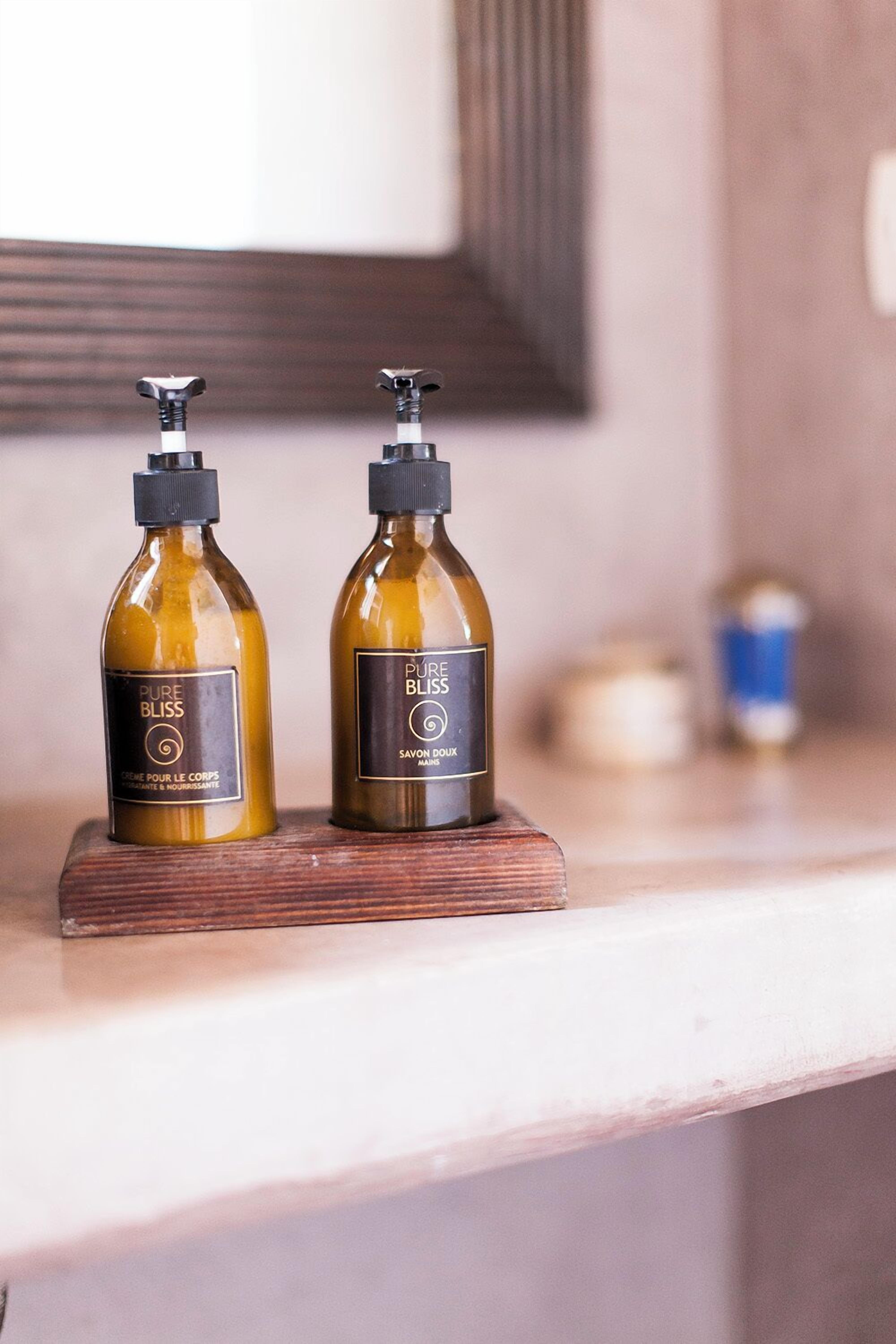 Two bottles of 'PURE BLISS' soap on a wooden tray on a countertop.