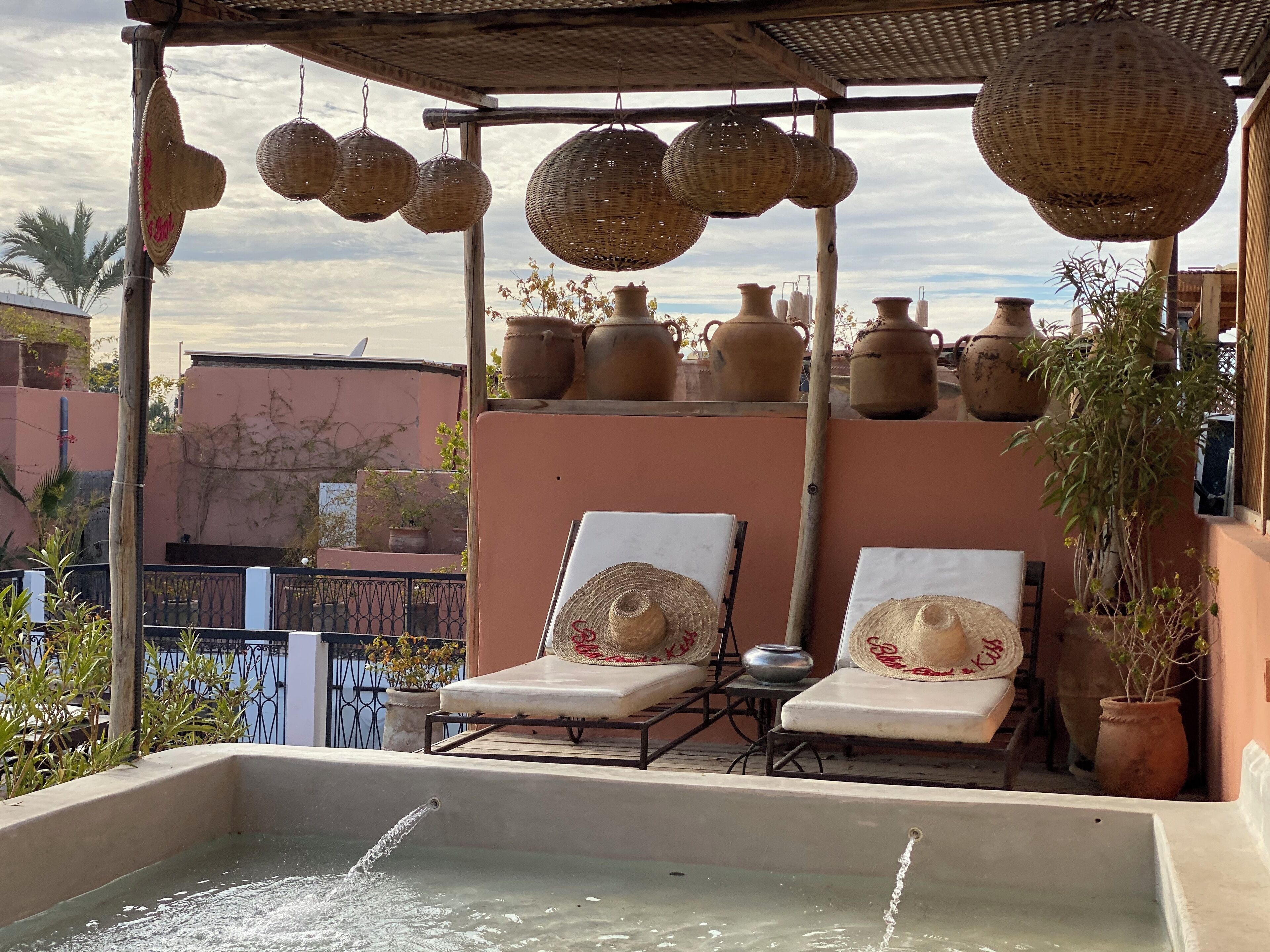 Una terraza en la azotea con dos sillones de relax, una mesita y una fuente de agua.